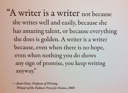 Texto impresso em fundo claro, aparentemente um painel de parede. Texto: ““A writer is a writer not because she writes well and easily, because she has amazing talent, or because everything she does is golden. A writer is a writer because, even when there is no hope, even when nothing you do shows any sign of promise, you keep writing anyway.”” / “— Junot Diaz, Professor of Writing, Winner of the Pulitzer Prize for Fiction, 2008”